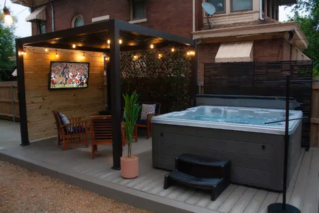 Outdoor living room and outdoor TV nestled under pergola.