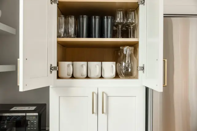 Fully stocked kitchen: water glasses, wine glasses, plastic cups, mugs, and a pitcher